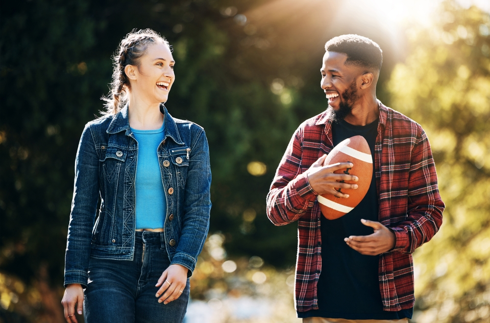 Couple,Laughing,,American,Football,In,Park,And,Happy,Together,In