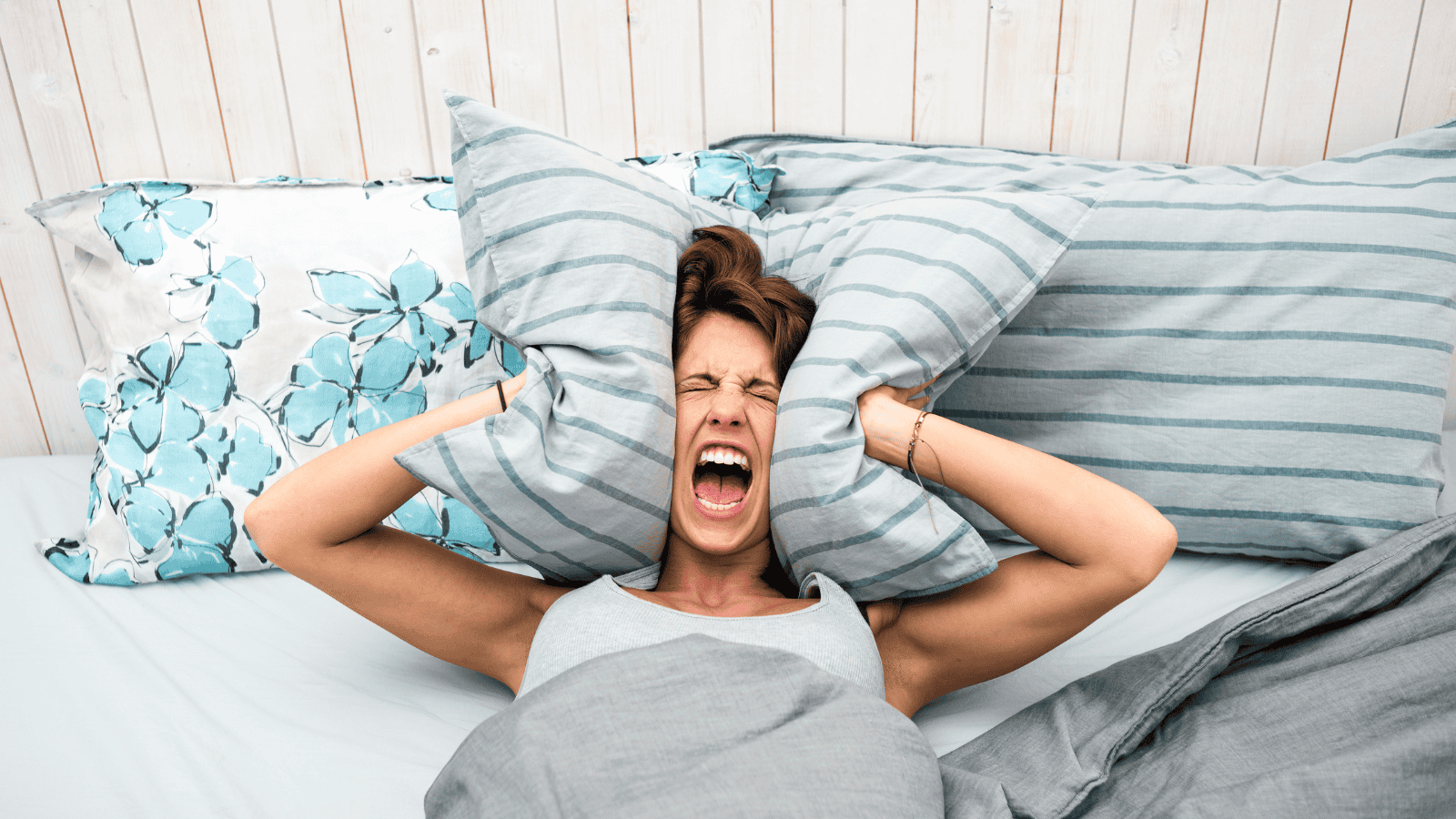 An overwhelmed woman is lying in bed, screaming