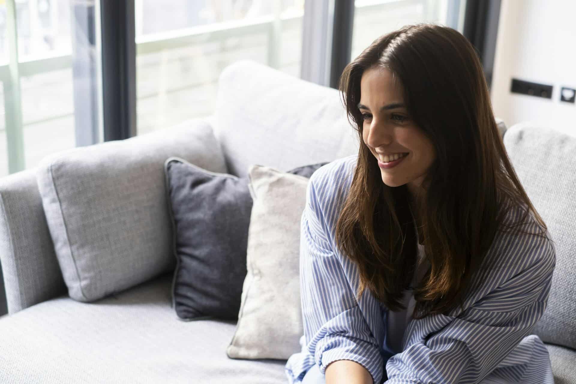Female psychological therapy session with girl sitting indoors on sofa smiling cheerfully