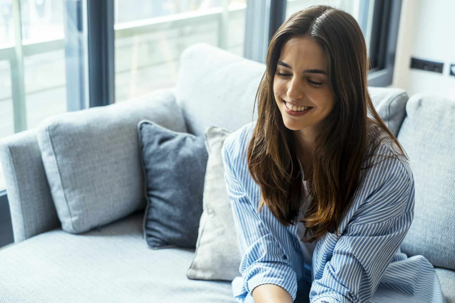 Female psychological therapy session with girl sitting indoors on sofa smiling