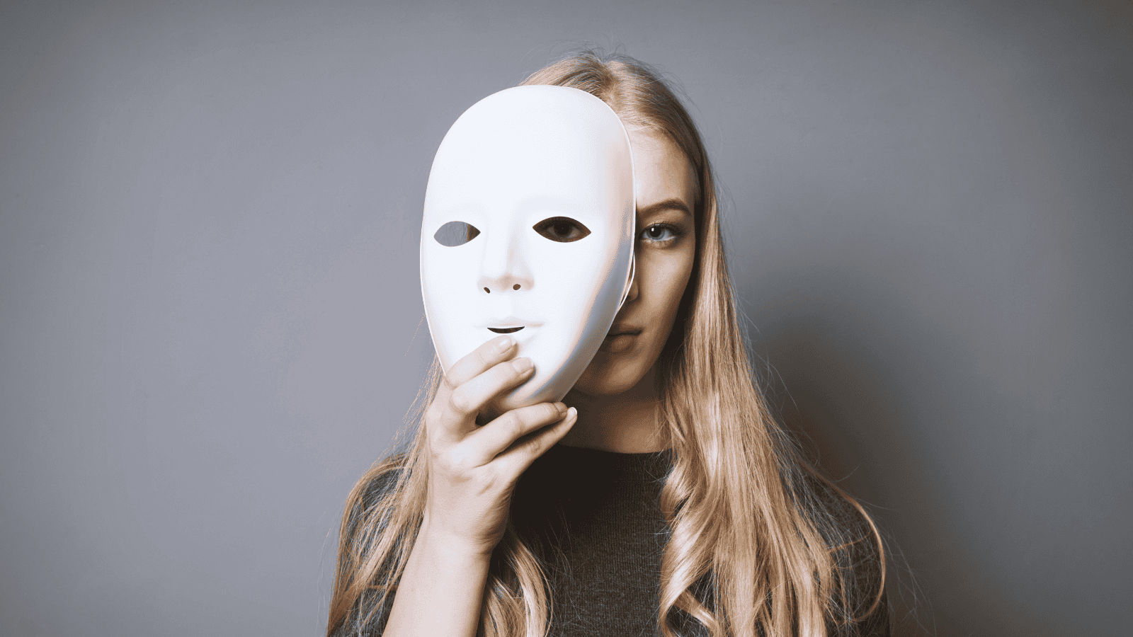 A teen girl with bipolar disorder hides her face behind a mask